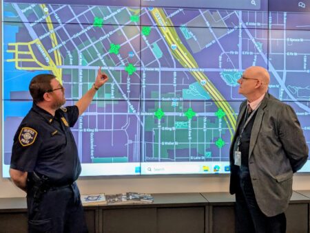 Police Lieutenant and Civilian Employee looking at a map on a large screen.